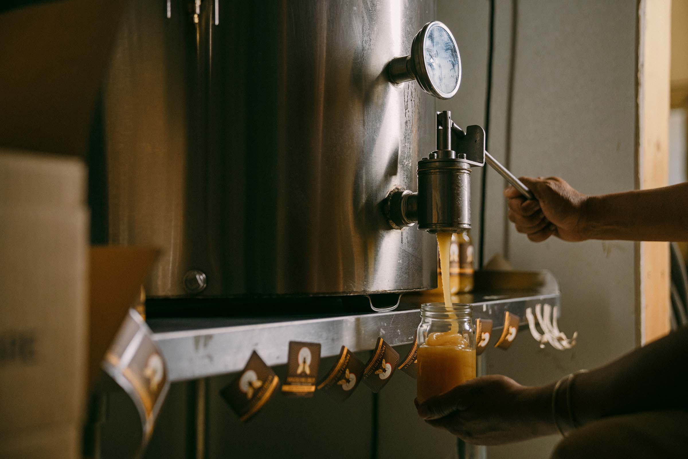 Person using dispensing raw honey into a jar