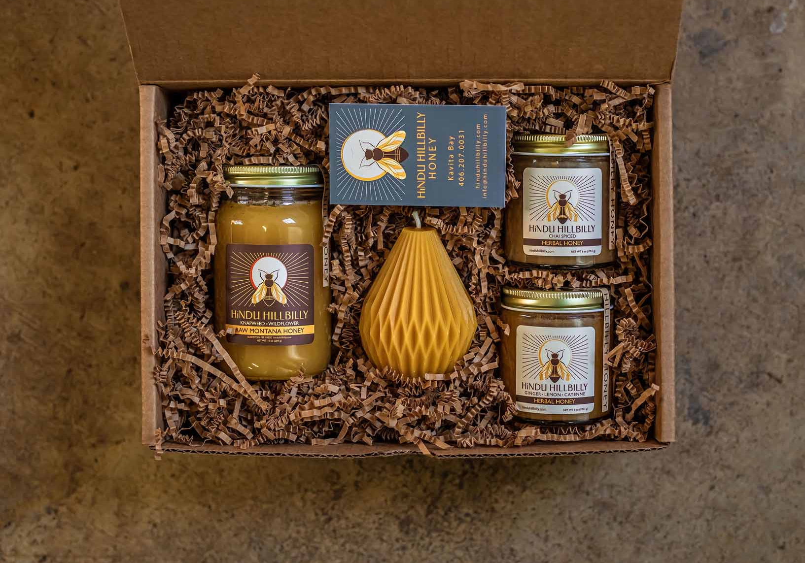 Gift set with jars and a honeycomb-shaped container in a box on a textured surface