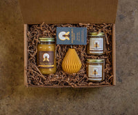 Gift set with jars and a honeycomb-shaped container in a box on a textured surface
