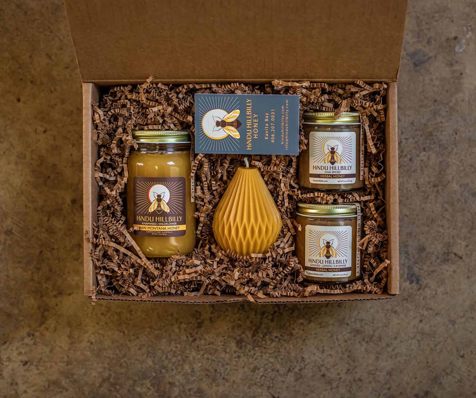 Gift set with jars and a honeycomb-shaped container in a box on a textured surface